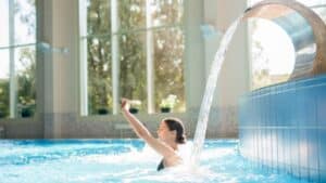 Mujer disfrutando de una piscina climatizada con sistema de aerotermia y chorro de agua.