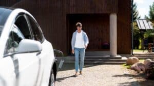 Joven dirigiendose a su coche eléctrico para recargarlo en otro edificio.